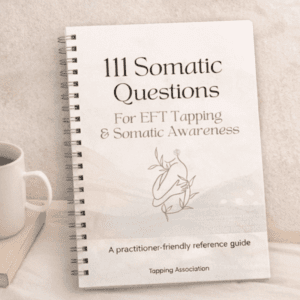 A spiral-bound "111 Somatic Questions for EFT Tapping – Practitioner Reference Guide (Printable PDF)" rests on a light surface beside a cup.