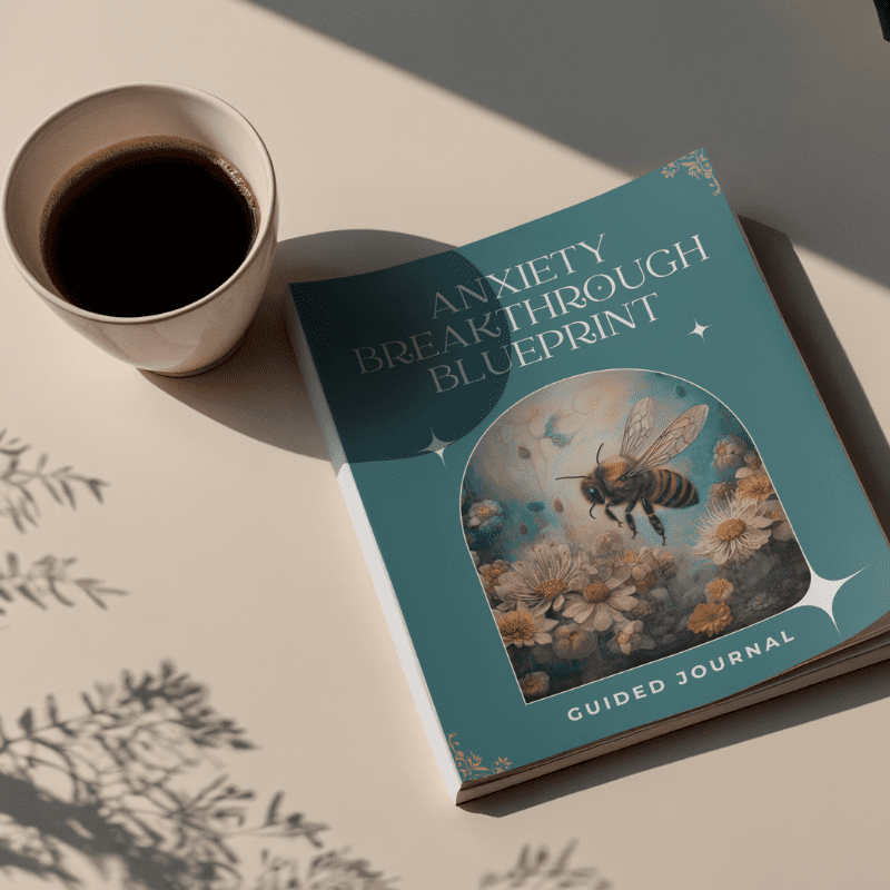 A cup of coffee sits beside the "Anxiety Breakthrough Blueprint – 4-Week Guided Journal for Anxiety Support," which features a bee and floral cover design, on a beige surface with plant shadows.
